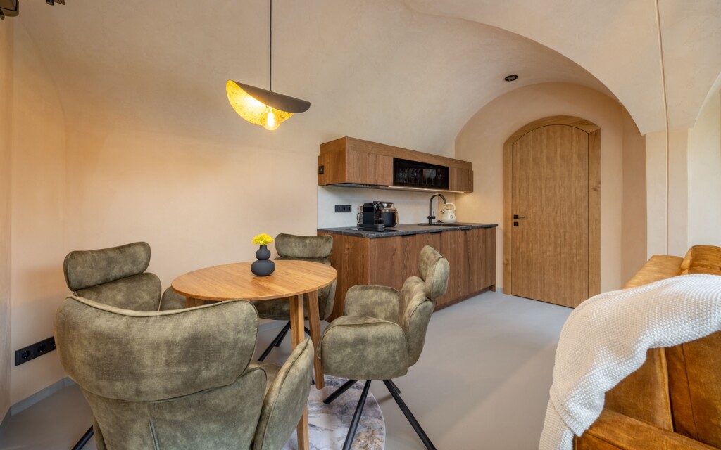 Revonia underground house open-plan interior – dining table, kitchen and bedroom in compact arched vault modular home
