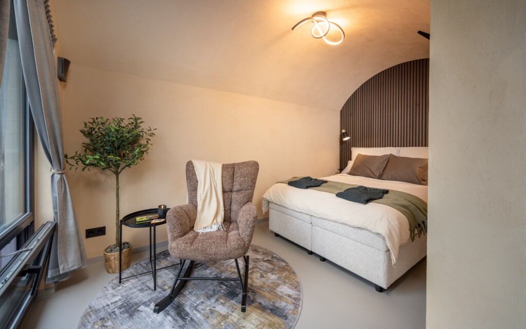 Revonia underground house bedroom – cozy double bed with arched vault ceiling and armchair in earth-sheltered modular home
